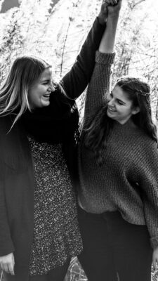 Schwarz-weiß Bild von zwei Schwestern die ihre Hände fassen und in die Höhe strecken.