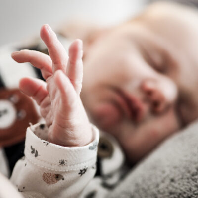 Baby im Schlaf mit seiner kleinen Hand im Vordergrund.