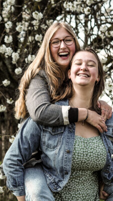 Mädel trägt Schwester huckepack.