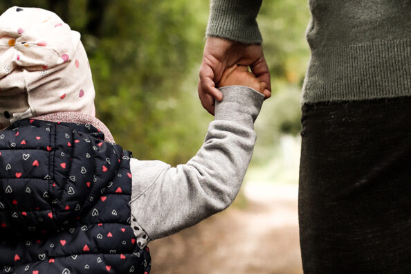 Mutter und Tochter spazieren Hand in Hand durch den Wald.