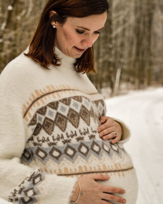 Babybauchshooting im winterlichen Outfit bei Schnee.