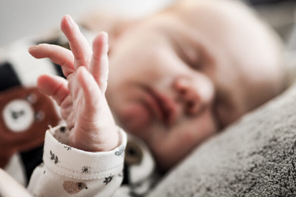Baby im Schlaf mit seiner kleinen Hand im Vordergrund.