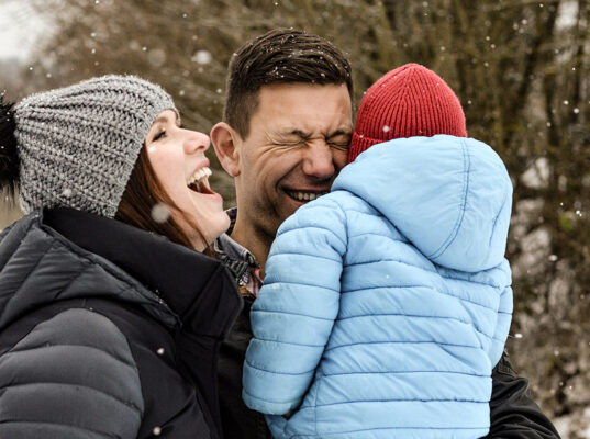 Familie lacht im Winter.